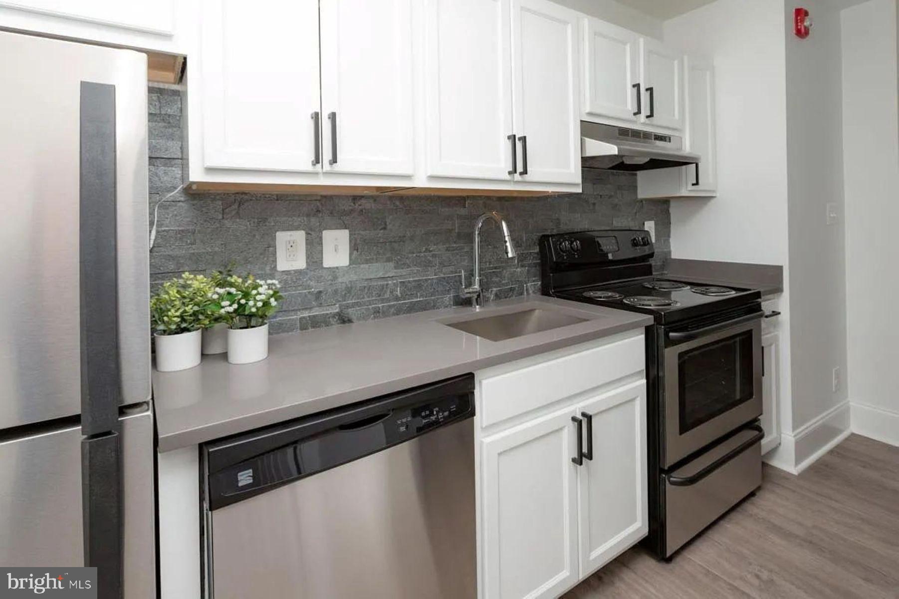1012 North Calvert Street, Unit 3B Baltimore, MD 21202 - Photo 2 of 9 a kitchen with stainless steel appliances granite countertop a stove a sink and a refrigerator
