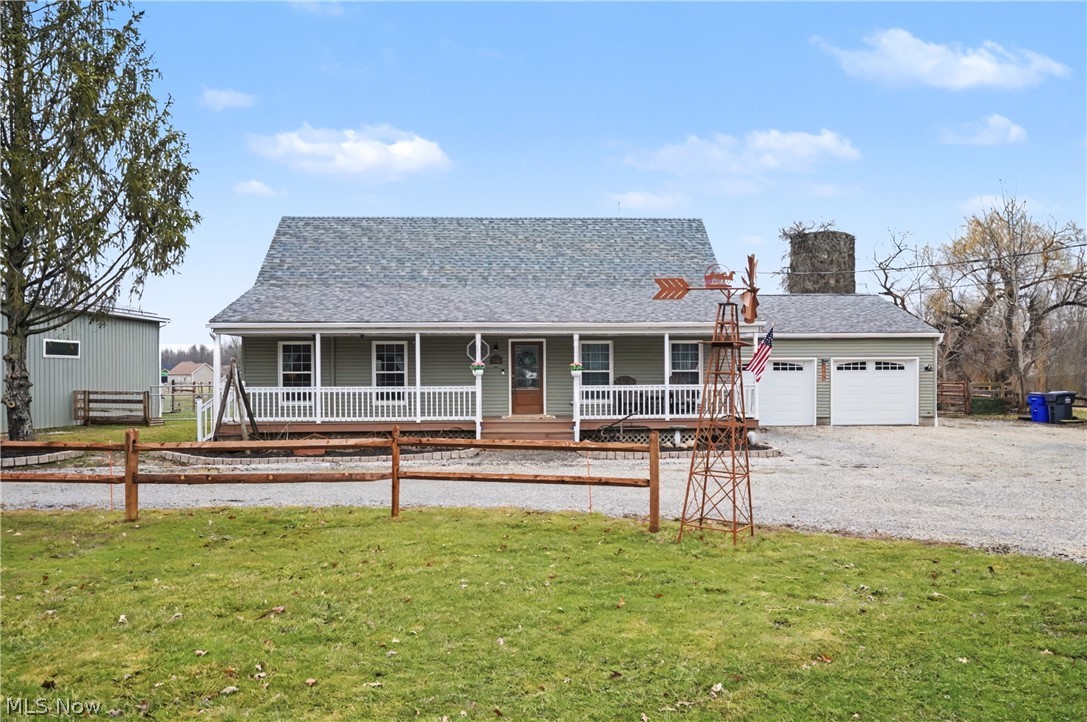 View of front facade featuring covered porch, a garage, driveway, and roof with shingles