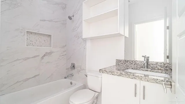 a bathroom with a granite countertop sink toilet and bathtub
