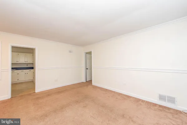 a view of kitchen with refrigerator and white cabinets