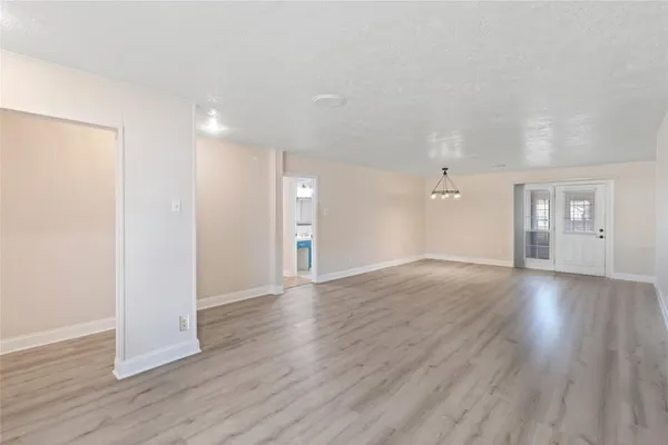 an empty room with wooden floor & windows and bathroom