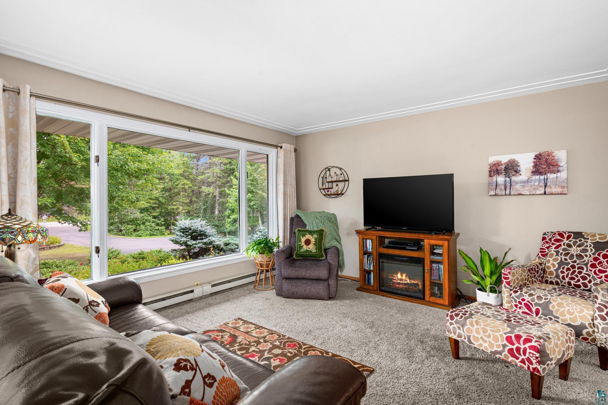 3727 Stebner Road Hermantown, MN 55811 - Photo 7 of 41 Expansive picture window, crown molding, light neutral wall color, plush carpet, and a built-in electric fireplace media console