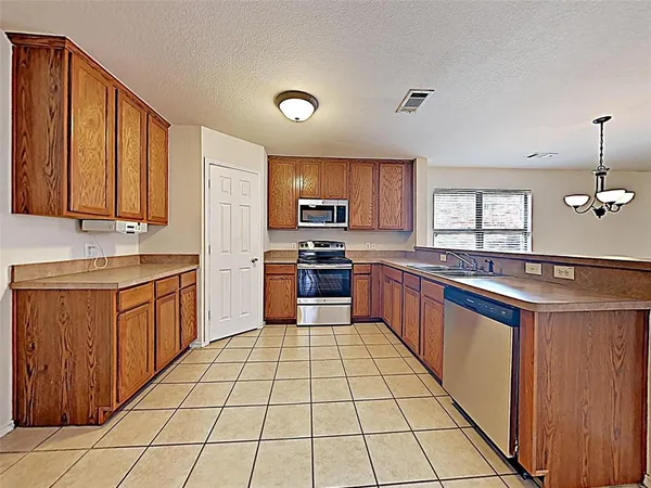 a large kitchen with a stove top oven a sink dishwasher and a refrigerator with wooden cabinets