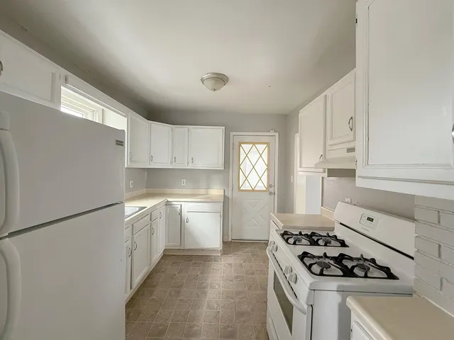 a kitchen with white cabinets and appliances