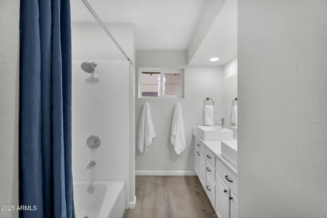 a bathroom with a double vanity sink a mirror and a bathtub