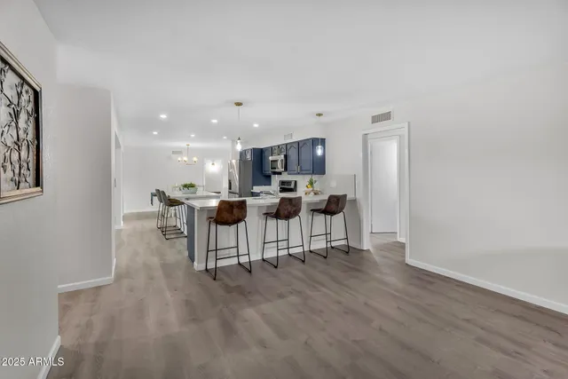 a kitchen with stainless steel appliances kitchen island granite countertop a stove a sink a refrigerator and chairs