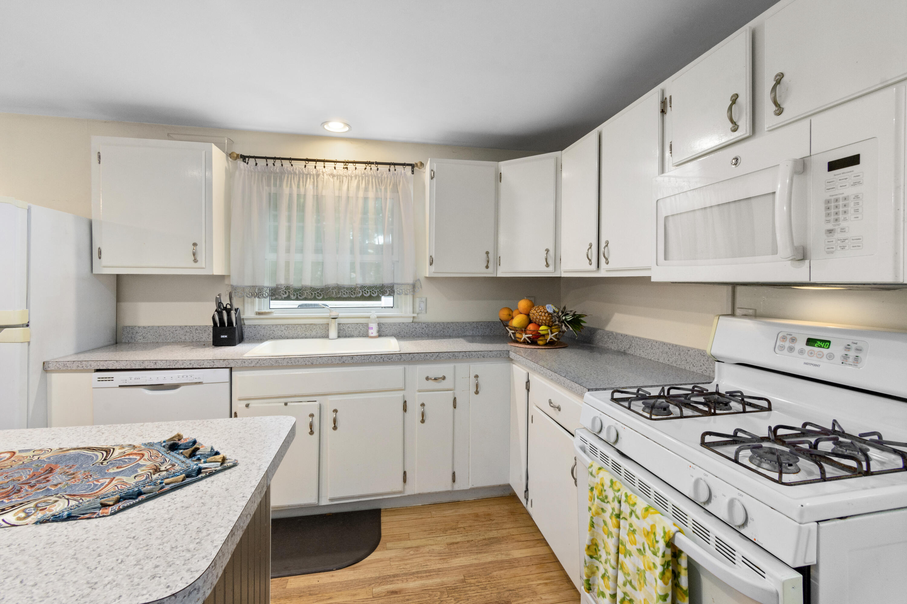 30 Patience Lane Cotuit, MA 02635 - Photo 7 of 27 a kitchen with stainless steel appliances granite countertop a stove a sink dishwasher and white cabinets with wooden floor