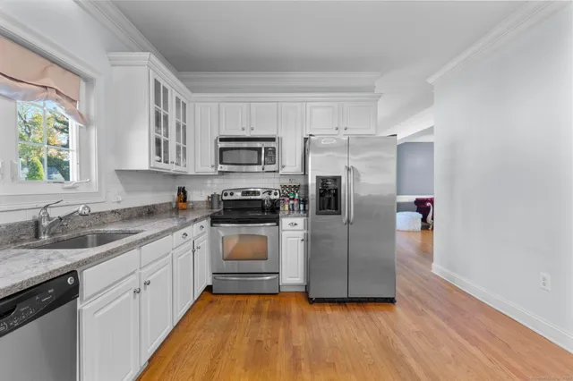 a kitchen with kitchen island granite countertop a sink cabinets and stainless steel appliances