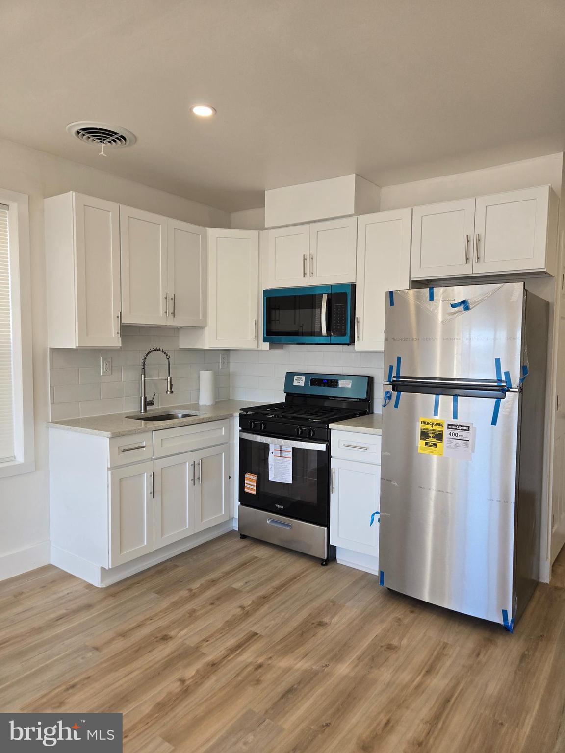 a kitchen with granite countertop a refrigerator and a stove top oven