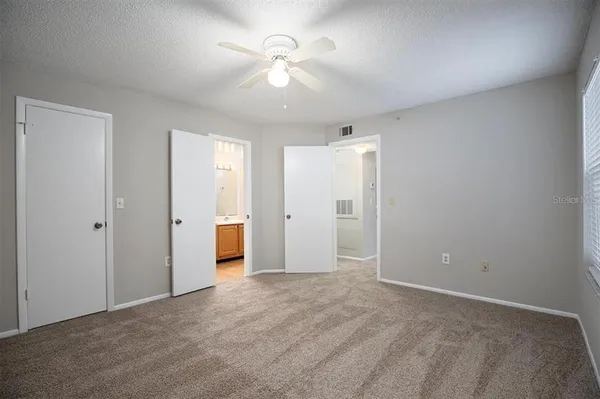 an empty room with windows and fan