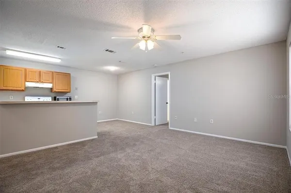 an empty room with windows and chandelier fan