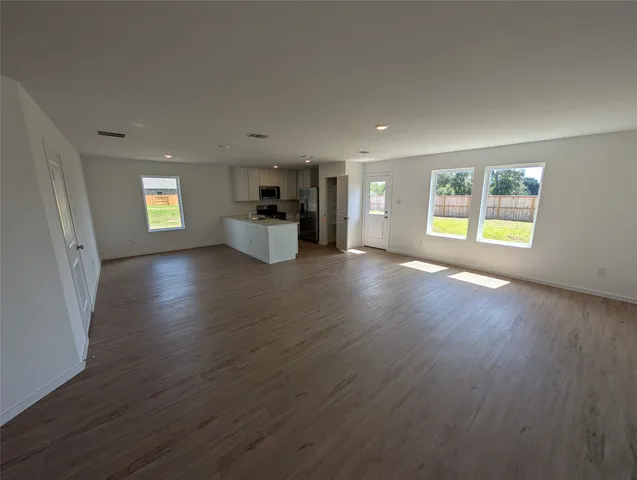 a view of a big room with wooden floor and windows