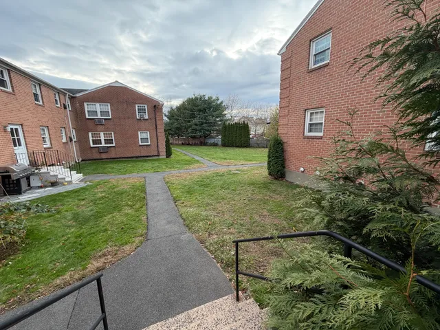 a view of a brick house next to a yard with big trees