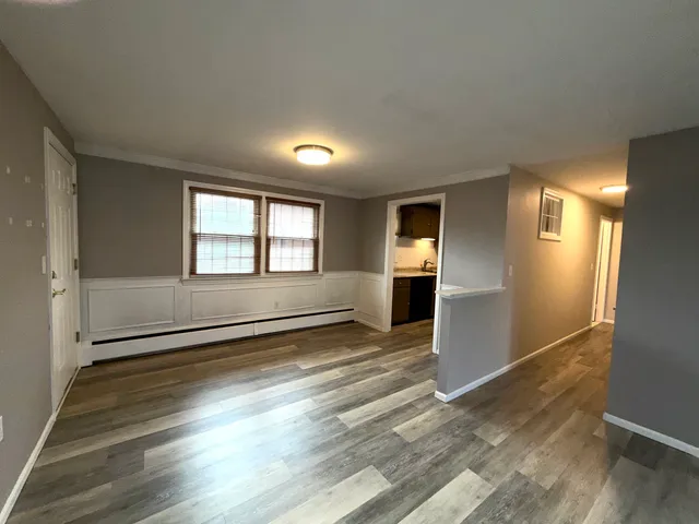 a view of empty room with kitchen and window