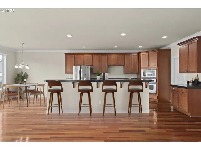 a kitchen with stainless steel appliances granite countertop a refrigerator a stove and a sink with wooden floors