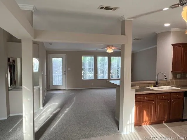an empty room with chandelier fan and windows