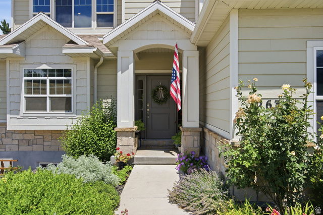 1263 East 1200th South Springville, UT 84663 - Photo 2 of 60 Inviting home entrance featuring a covered porch with stone-clad columns, a dark panel door, and a concrete walkway