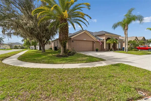 a view of a house with a yard and palm trees