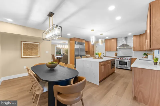 a kitchen with stainless steel appliances granite countertop a sink a stove a dining table and chairs