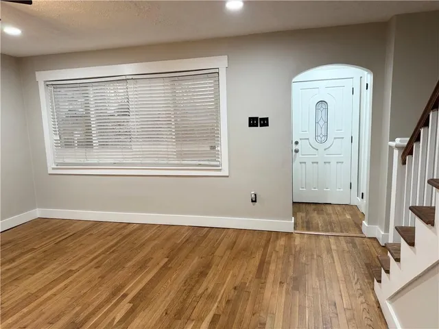 an empty room with wooden floor cabinet and windows