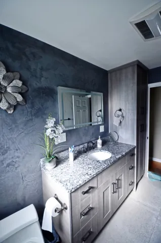a bathroom with a granite countertop sink a toilet and mirror