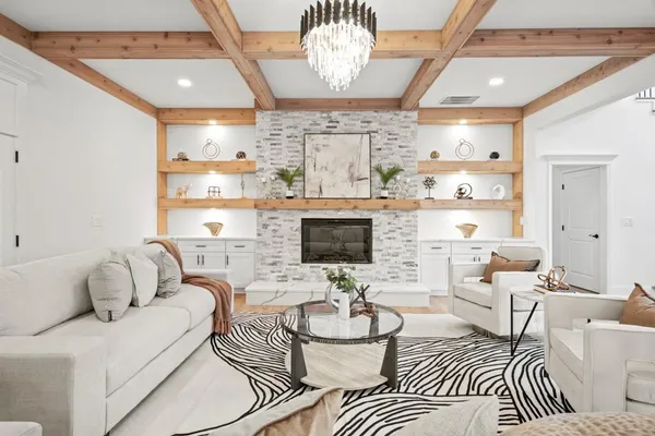 a living room with furniture kitchen view and a chandelier