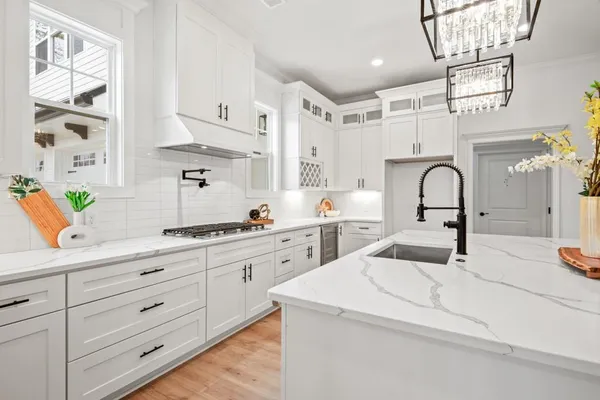 a large white kitchen with lots of counter space and wooden floor