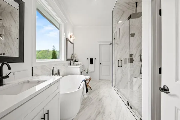 a bathroom with a white tub sink vanity mirror and toilet