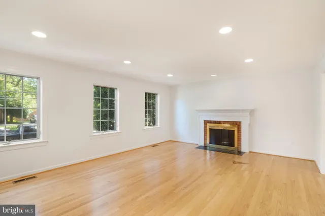 a view of an empty room with wooden floor and a fireplace