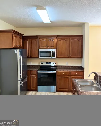 a kitchen with stainless steel appliances granite countertop a refrigerator stove and sink