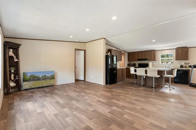 a living room with furniture large window and kitchen view