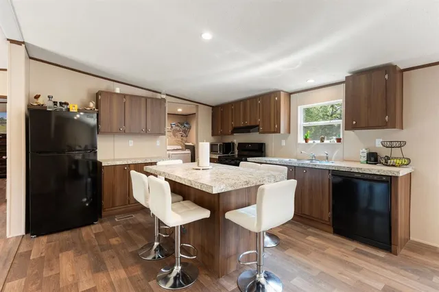 a kitchen with granite countertop a refrigerator stove microwave and sink
