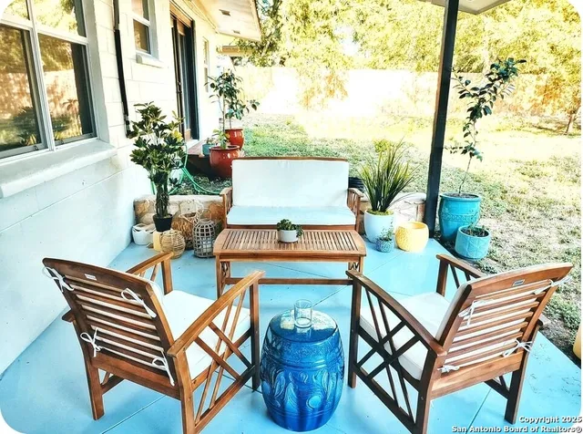 a living room with patio furniture and floor to ceiling windows
