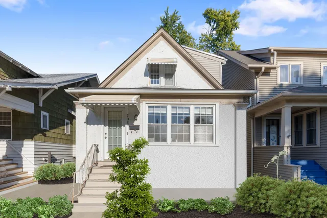 a view of a white house with potted plants and a table and chairs