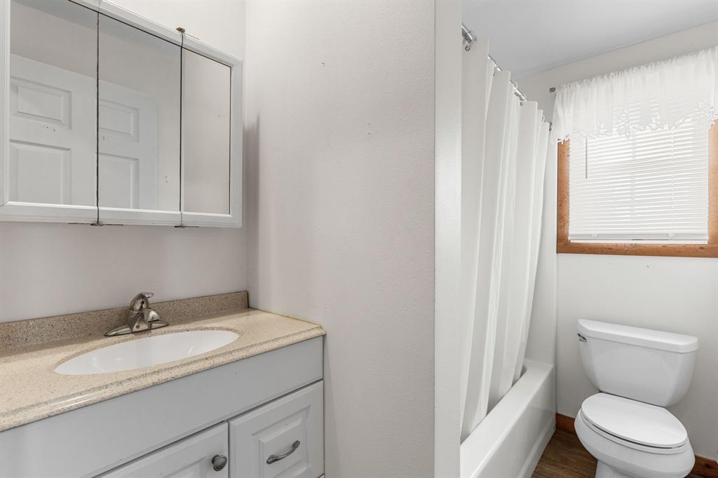 13315 Highway 281 Scotland, TX 76379 - Photo 37 of 40 Full bathroom featuring a white vanity with an integrated sink, a speckled countertop, and a mirrored medicine cabinet