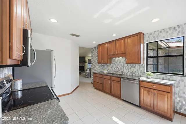 a kitchen with stainless steel appliances granite countertop a stove a sink and a microwave