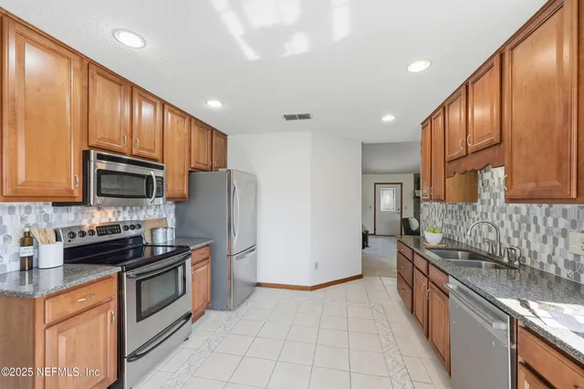 a kitchen with stainless steel appliances granite countertop wooden cabinets a sink dishwasher a refrigerator and a stove