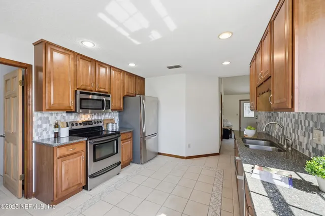 a kitchen with stainless steel appliances granite countertop a refrigerator a stove top oven and sink