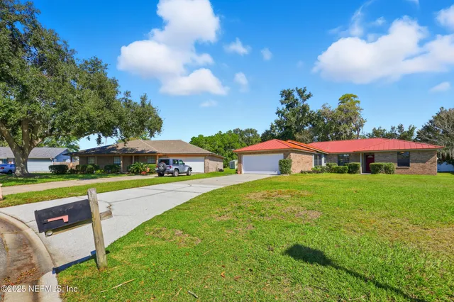 a view of a house with a yard and table and chairs under an umbrella