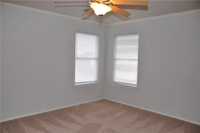 an empty room with a chandelier fan and windows