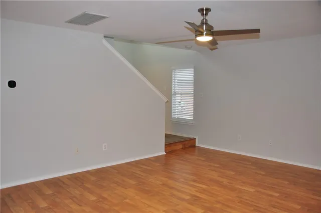 a view of an empty room with a ceiling fan and a fan