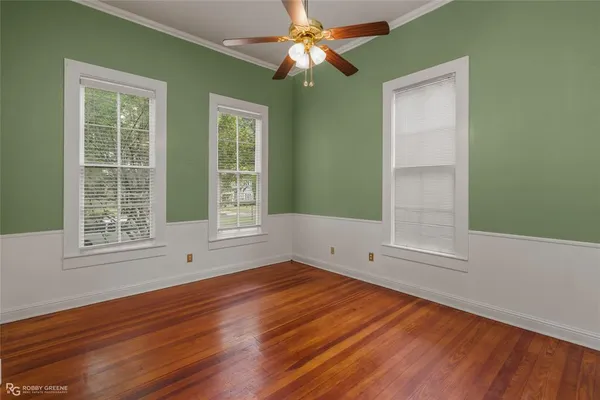 an empty room with wooden floor cabinet and windows