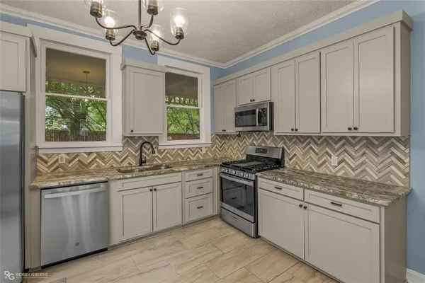 a kitchen with stainless steel appliances granite countertop a sink dishwasher a stove and a microwave oven with cabinets