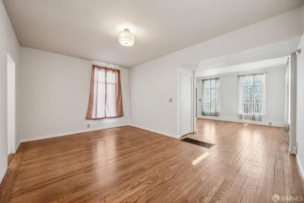 a view of an empty room with wooden floor and a window