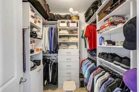 a view of walk in closet with clothes and shoes