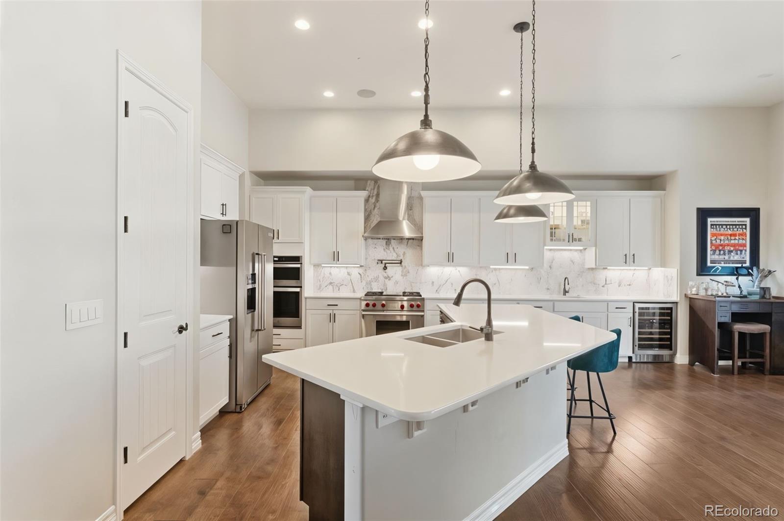 5318 Rocking Tree Grove Colorado Springs, CO 80906 - Photo 9 of 50 a kitchen with stainless steel appliances kitchen island granite countertop a table a stove a refrigerator and a sink with wooden floor