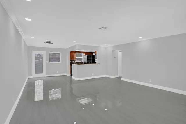 a view of an empty room with a window and wooden floor