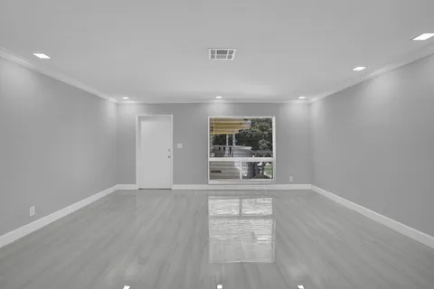 a view of an empty room with a window and wooden floor
