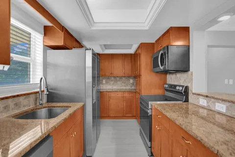 a kitchen with stainless steel appliances granite countertop a sink a stove and a wooden floors