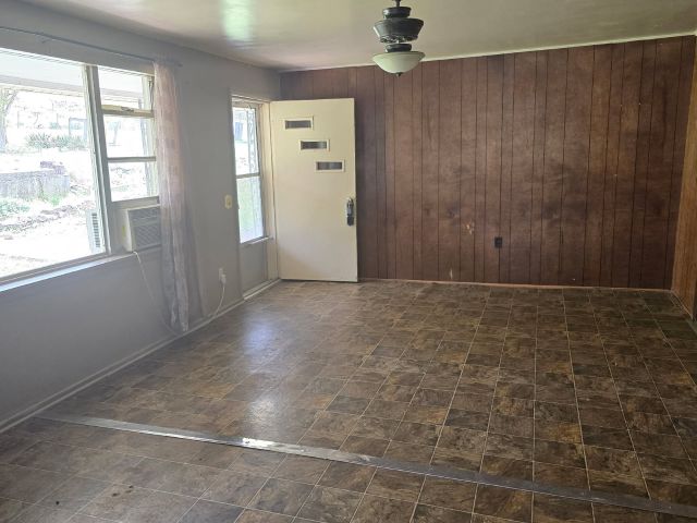 400 Canaan Road Marshall, AR 72650 - Photo 6 of 18 Living area featuring patterned floor tiles, wood paneling on one wall, and windows providing natural light
